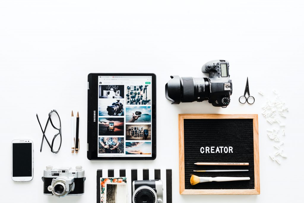 Flatlay von ipad, Fotokamera, Smartphone und Brille in der Influencer Ausbildung