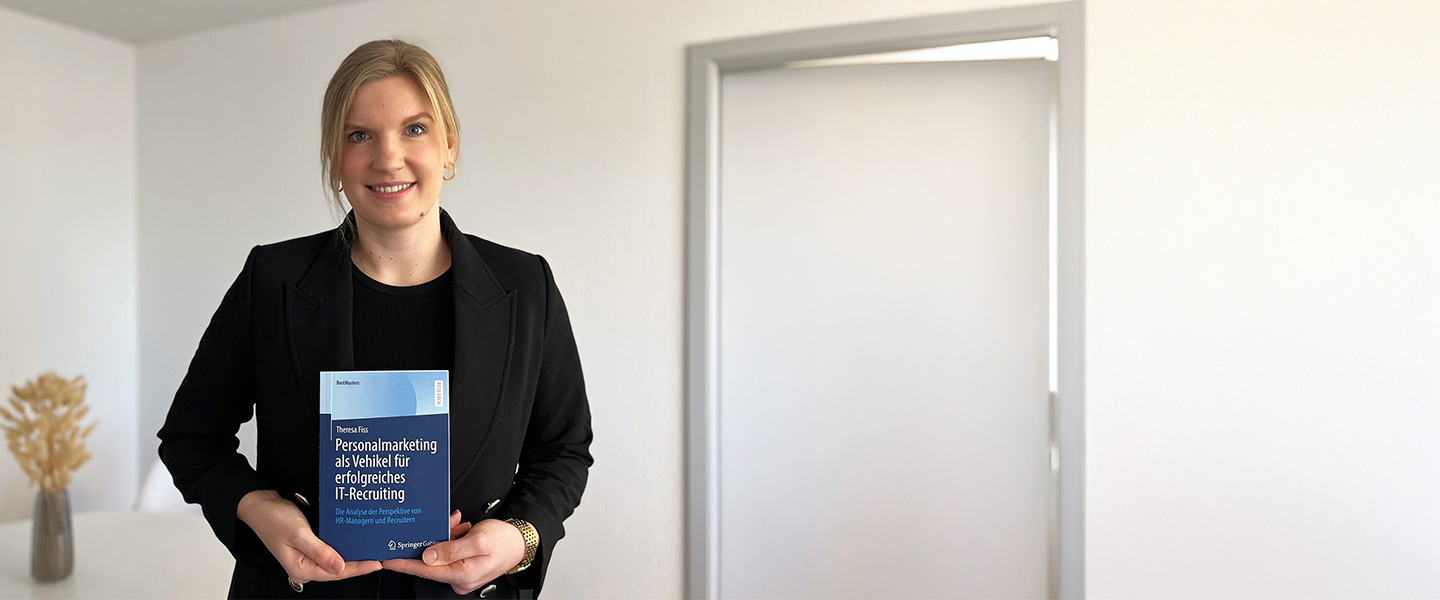 Masterabsolventin Theresa Fiss hält ihr Buch in die Kamera