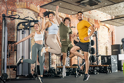 Junge Fitnesstrainer:innen springen vor Freude in die Höhe