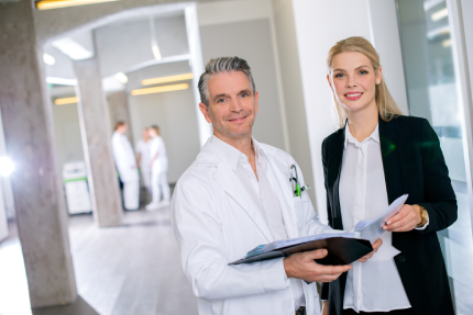 Arzt und Managerin im Krankenhausflur über Akten