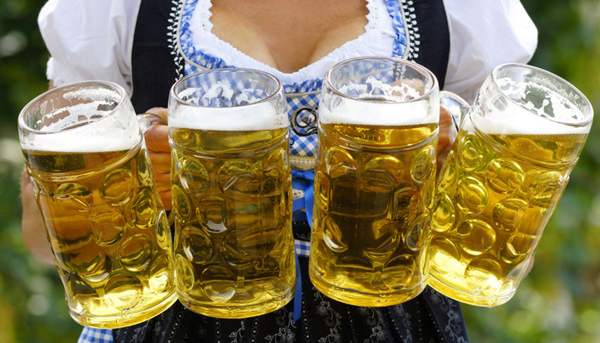 Frau im Dirndl trägt Maßkrüge