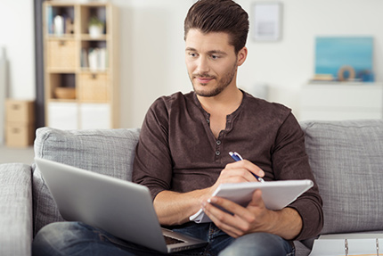 Mann mit Laptop auf Sofa