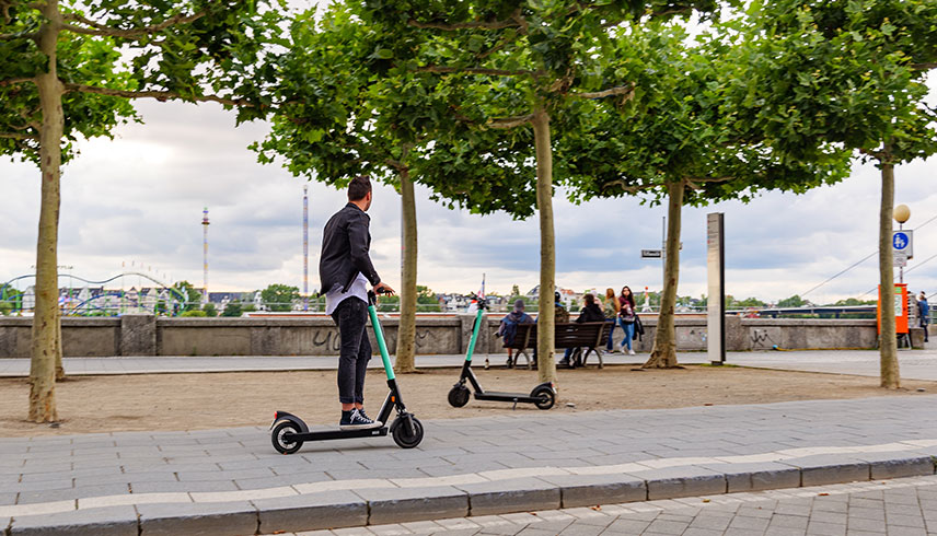 Mann auf E-Roller an Promenade