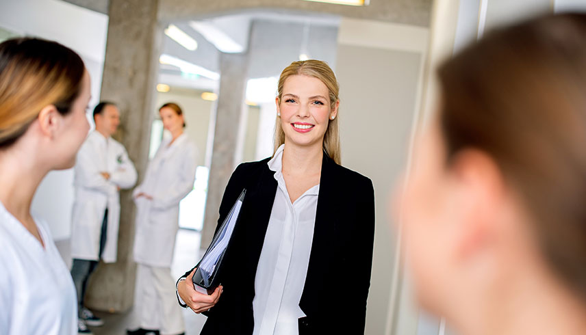 Frau neben Ärzten Ausbildung Gesundheitsmanagerin