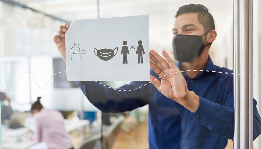 Person mit Maske und Hinweisschild