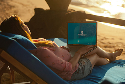 Frau auf einer Liege am Strand mit Laptop