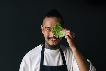 Veganer Koch mit Salatblatt am Auge
