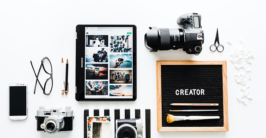 Flatlay von ipad, Fotokamera, Smartphone und Brille in der Influencer Ausbildung
