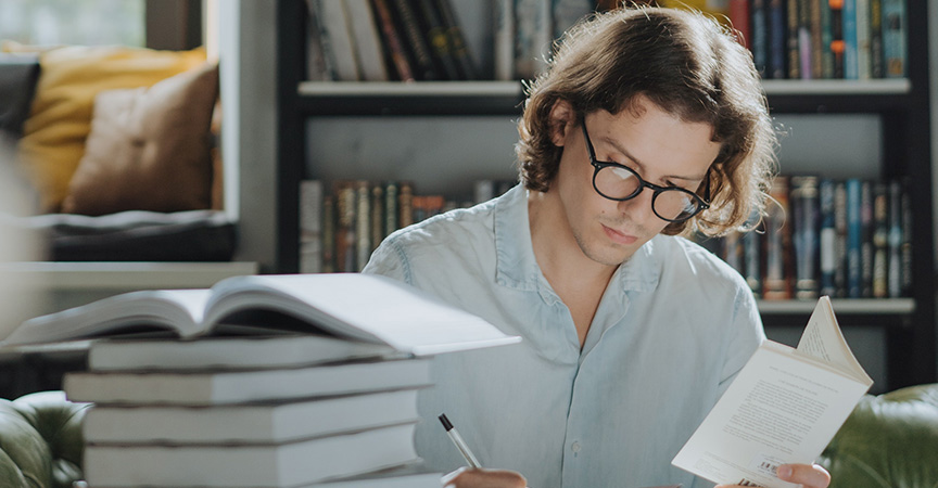 Mann an Schreibtisch mit Büchern
