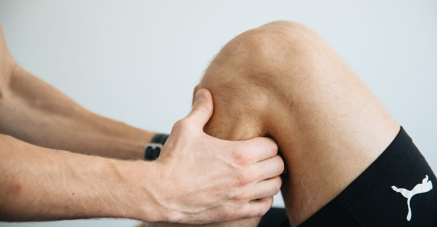 Sporttherapeut untersucht Knie