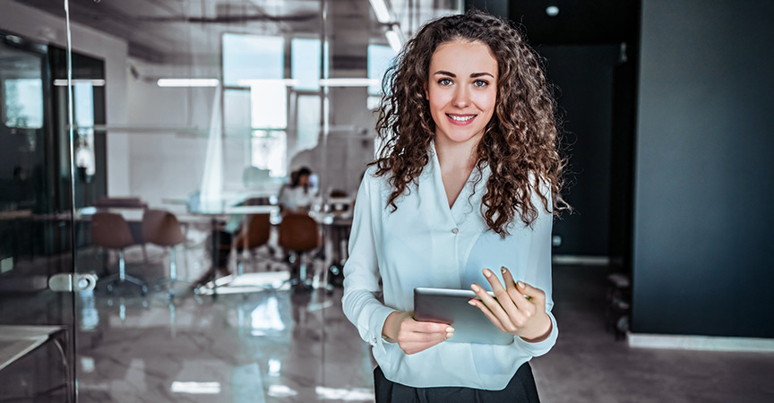 Frau mit Unterlagen im Arm blickt in die Kamera