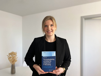 Masterabsolventin Theresa Fiss hält ihr Buch in die Kamera